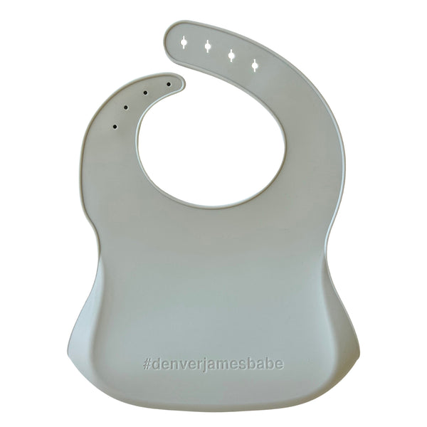 Back view of a green Silicone bib on a white background with '#denverjamesbabe' text.