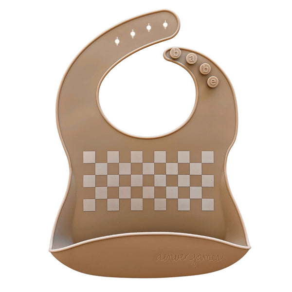 Front view of a tan food catcher bib with a white checkered pattern on a white background, clasps read 'babe' while the 'denver james' logo is imprinted on the bottom.
