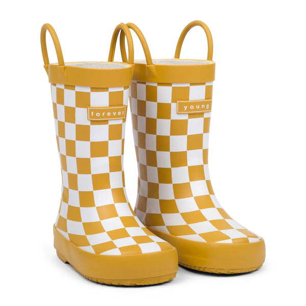 Front 3/4 view of golden and white checkered children's rain boots with 'forever young' branding on a white background.