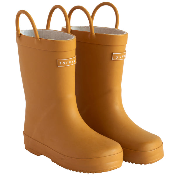 Front 3/4 view of a pair of golden colored rain boots for children. Showing pull handles for easy slip on and tags that say "Forever Young" on the front.