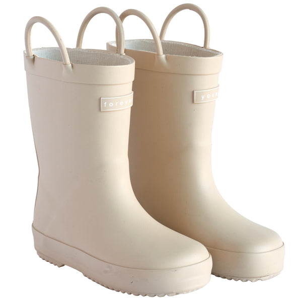 Front 3/4 view of a pair of sand colored rain boots for children. Showing pull handles for easy slip on and tags that say "Forever Young" on the front.