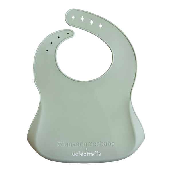 Back view of a light green silicone bib on a white background with '#denverjamesbabe' text and 'x @alectreffs' in white text.