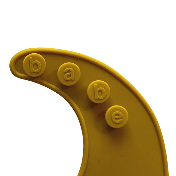 detail image of a dark orange silicone bib on a white background with 'babe' buttons.