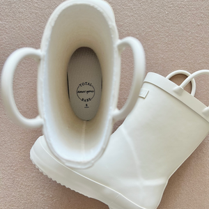 Lifestyle detail image of sand colored children's rain boots focusing on the insole that says 'Total Babe, Denver James' with the size. 