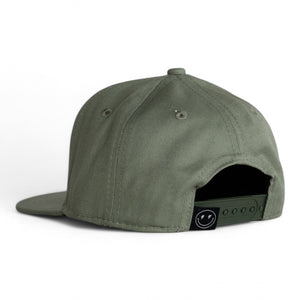 back 3/4 view of green 6 panel black baseball cap with a snap back and smiley face with lighting bolt eyes tag on white backdrop. 