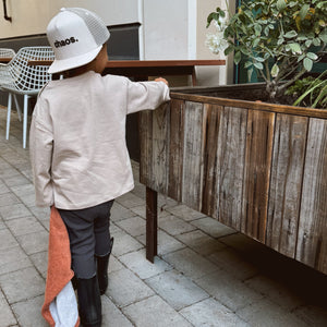 Boy wearing backwards hat that says 'Chaos' walking in a courtyard. 