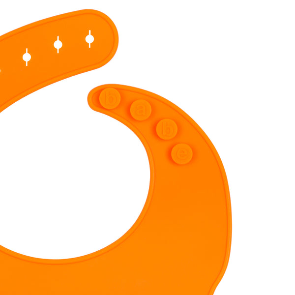 Detail View of a bright orange silicone food catcher bib on a white background with buttons that state 'babe'. 