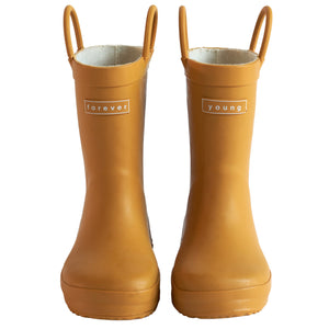 Front view of a pair of golden colored rain boots for children. Showing pull handles for easy slip on and tags that say "Forever Young" on the front. 