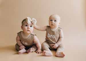 Two babies - one girl wearing sis romper, one boy wearing bro romper