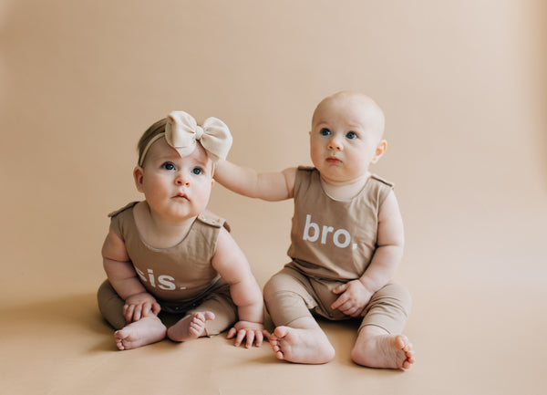 Two babies - one girl wearing sis romper, one boy wearing bro romper