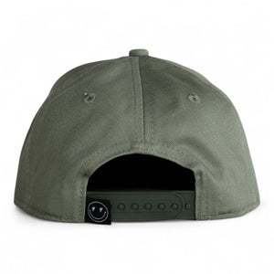 back view of green 6 panel black baseball cap with a snap back and smiley face with lighting bolt eyes tag on white backdrop. 