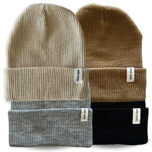 Four folded knit beanie hats in gray, brown, and black and tan with visible brand labels on a white background.