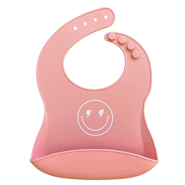 Front view of a  Pink silicone food catcher bib with a smiley face design on a white background
