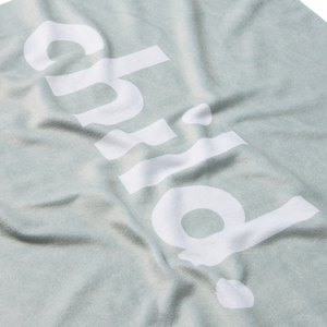 a detailed shot of a green microfiber beach towel with the word 'child.' printed in large white letters. 
