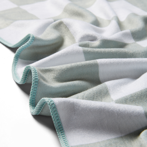 a detailed image of a green microfiber towel showing the edge stitching as well as the texture of the towel.