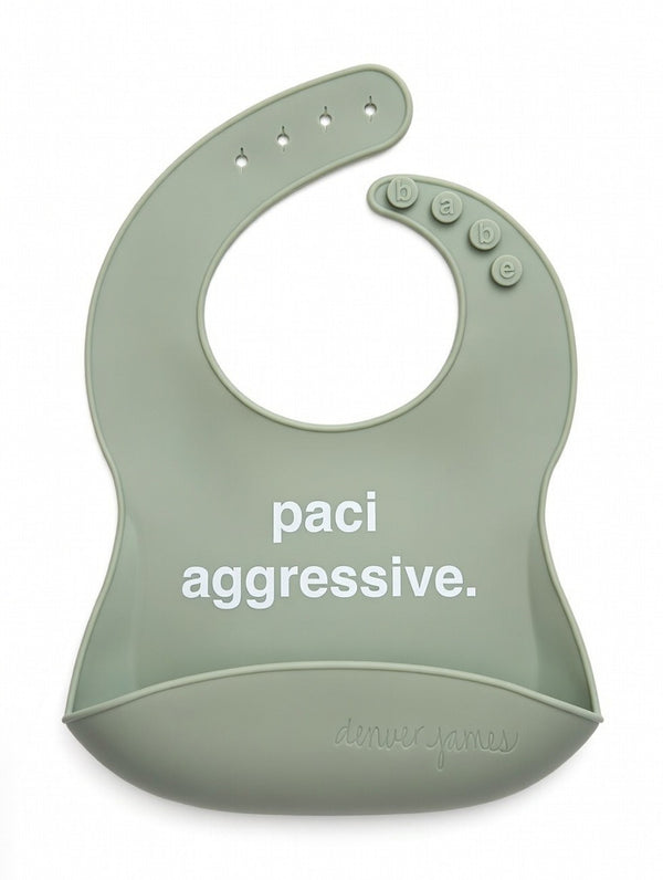 Front View of a mute green silicone food catcher bib with 'paci aggressive.' text on a white background.