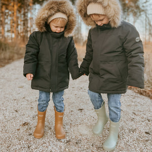 Lifestyle image of 2 boys wearing solid colored children's rubber rain boots. 