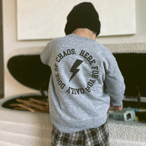 A child wearing an ash gray crew sweatshirt with text and a lightning bolt design on the back.