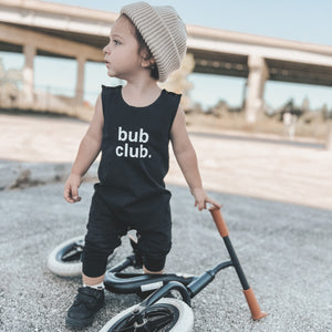 Toddler riding bike while wearing romper and beanie. 