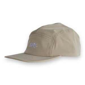 Front 3/4 view of a tan five-panel cap with the word 'salty.' embroidered on the front on a white backdrop. 