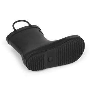 Detail image of black rubber children's rain boot with a textured sole on a white background with pull handles. 