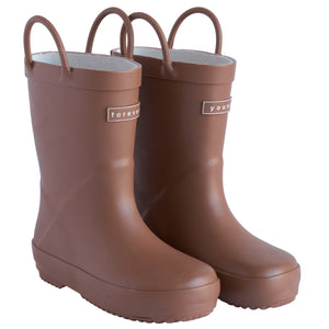 Front 3/4 view of a pair of chocolate colored rain boots for children. Showing pull handles for easy slip on and tags that say "Forever Young" on the front. 