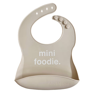Front View of a light grey silicone food catcher bib with 'mini foodie.' text on a white background.
